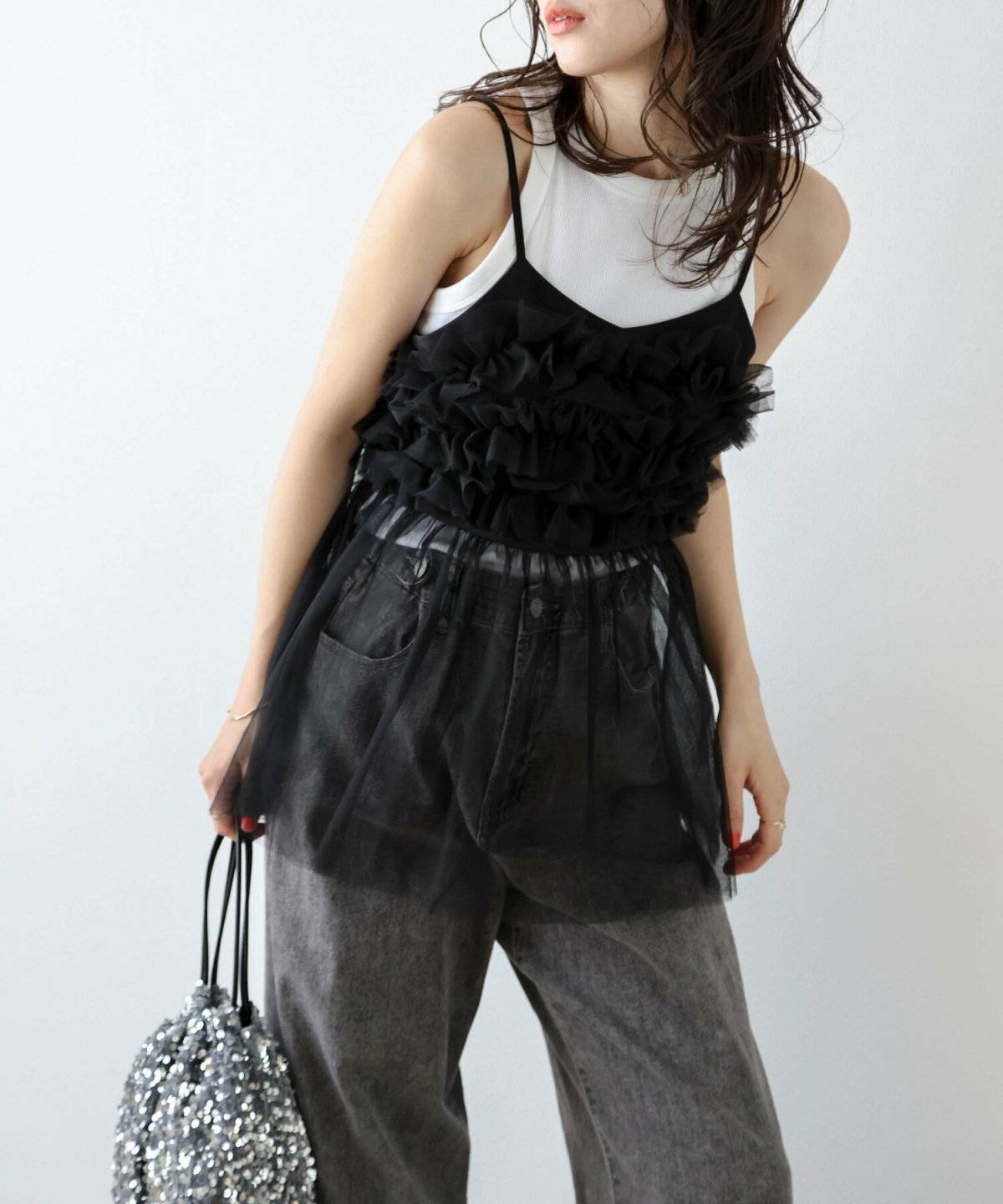 チュールのキャミソールを重ねてデニムを穿いた女性