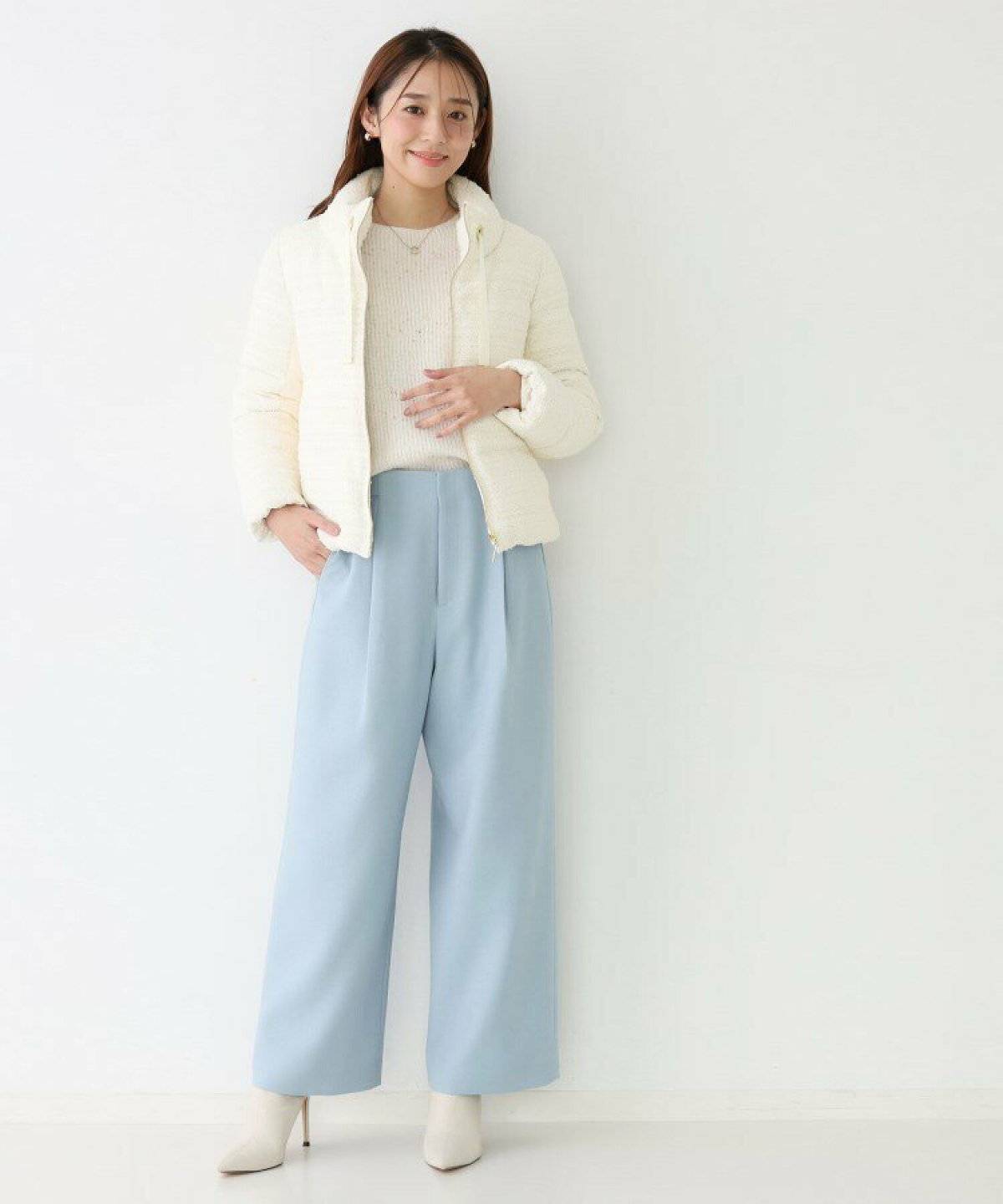 白のダウンに水色のパンツを穿いた女性