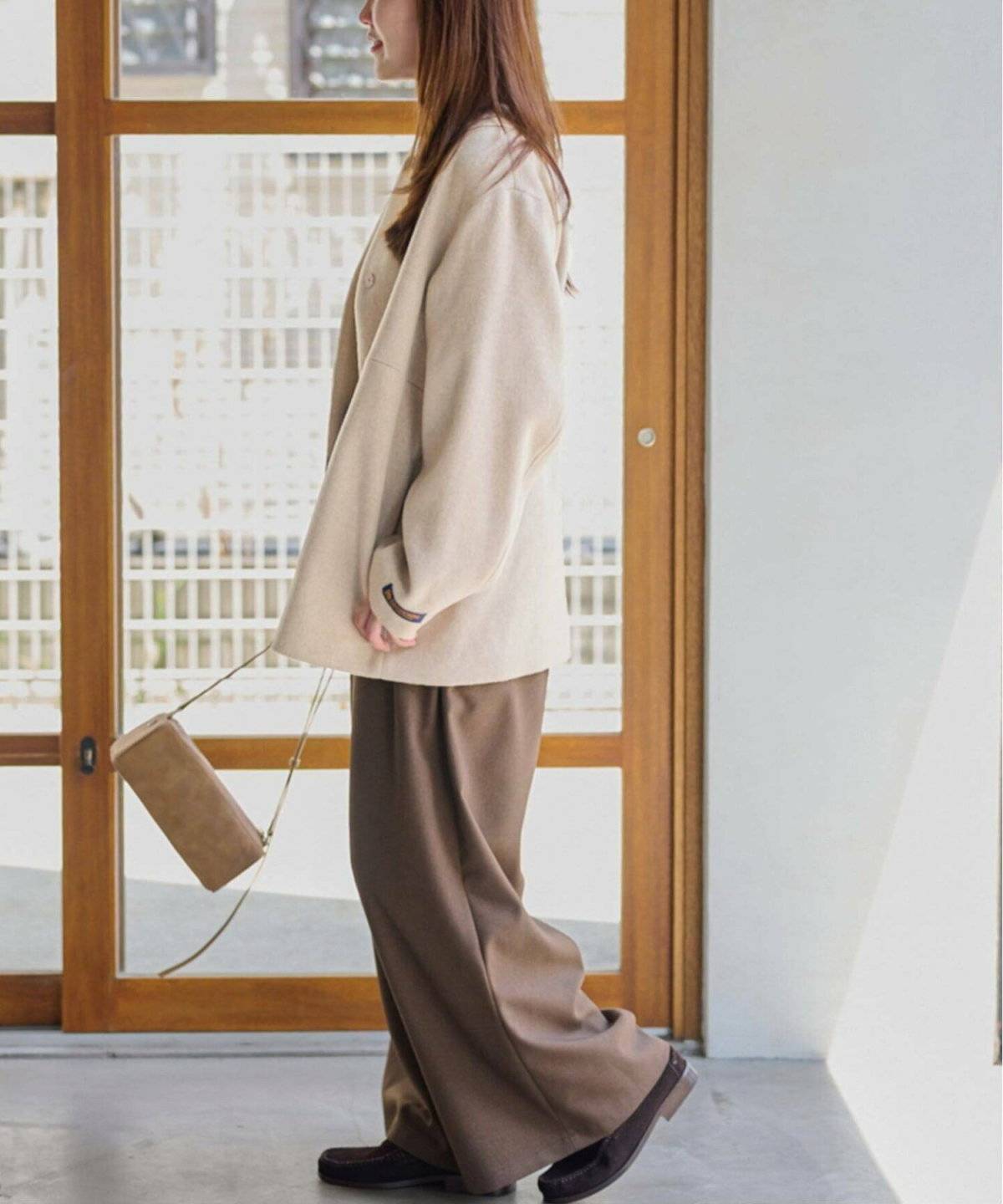 ベージュのコートにブラウンのパンツを合わせた女性