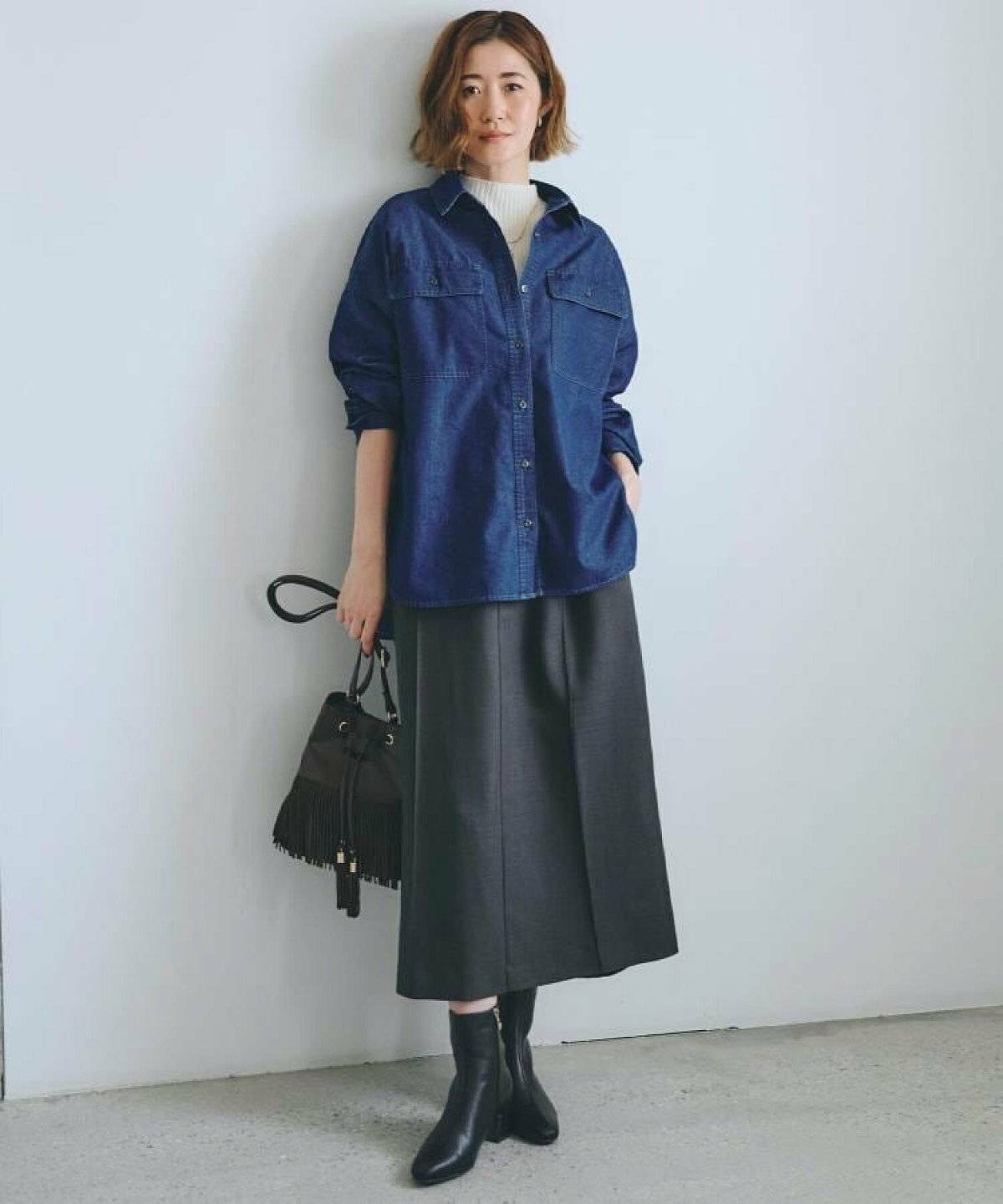 ニットにデニムシャツを重ねてスカートを合わせた女性
