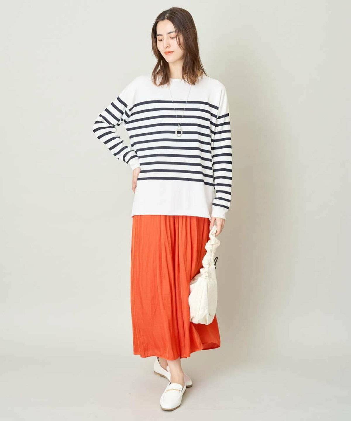 ボーダー柄ニットにオレンジのスカートを合わせた女性