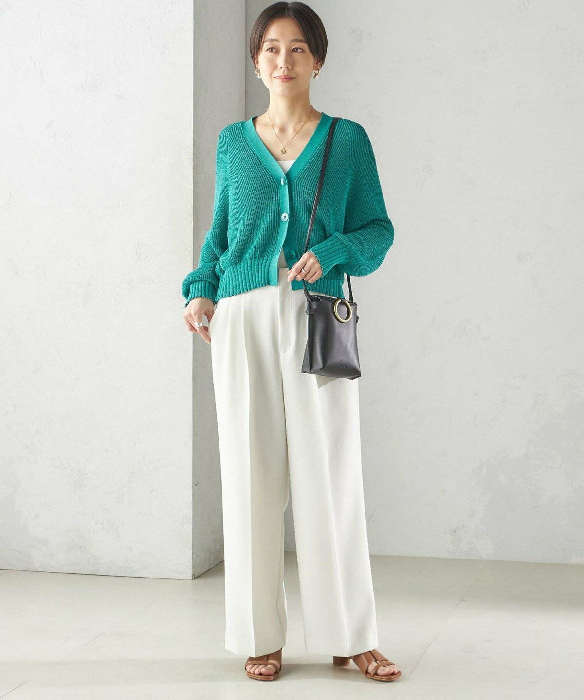 グリーンニットに白パンツを合わせた女性