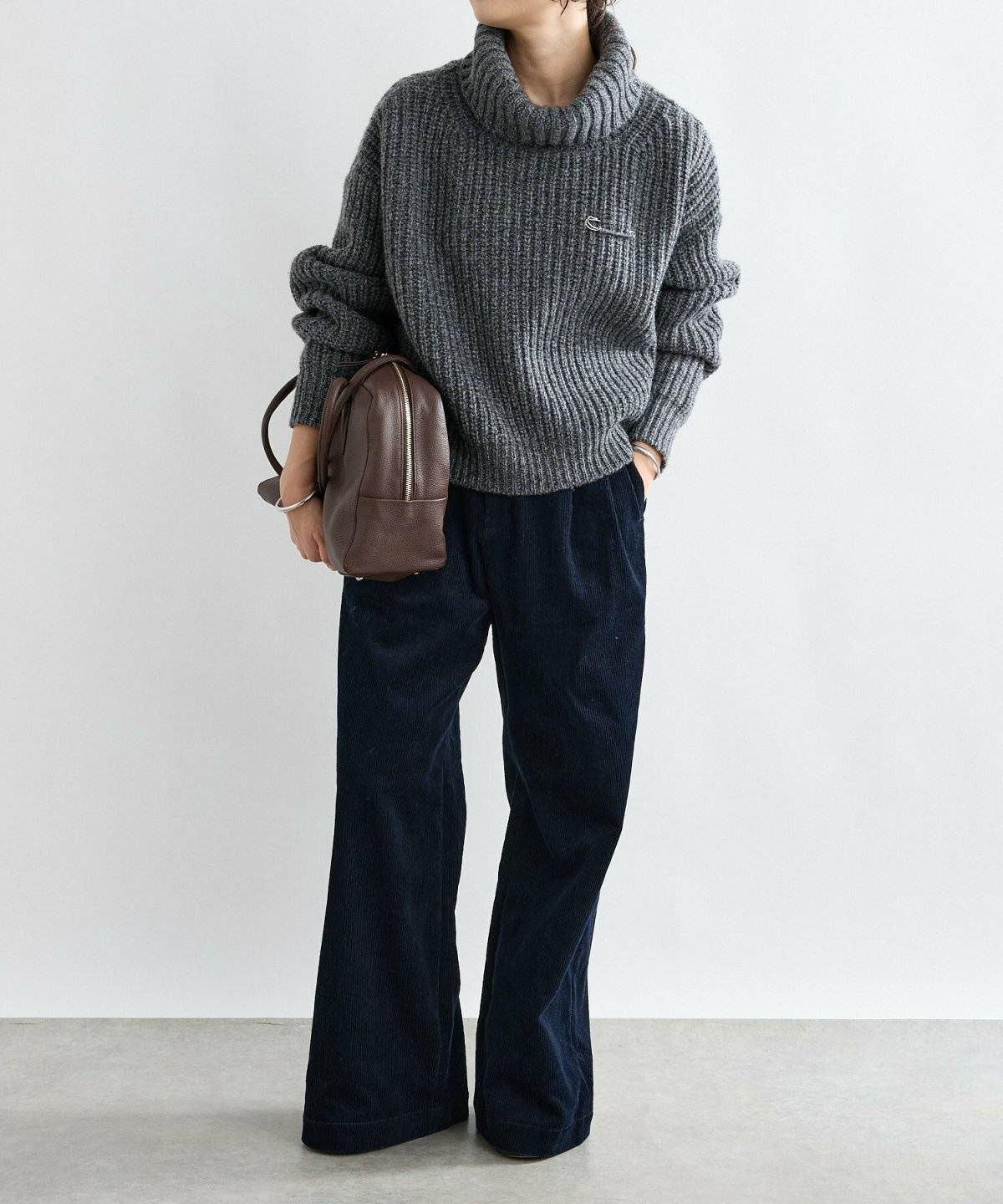 グレーのニットに黒パンツを合わせた女性