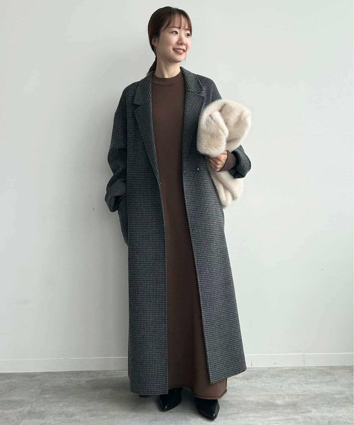 ブラウンワンピースにロングコートを羽織った女性