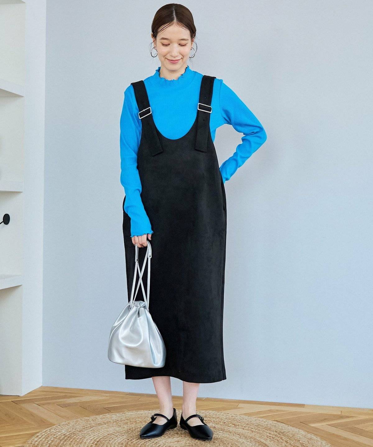 青ニットに黒ワンピースを重ねた女性
