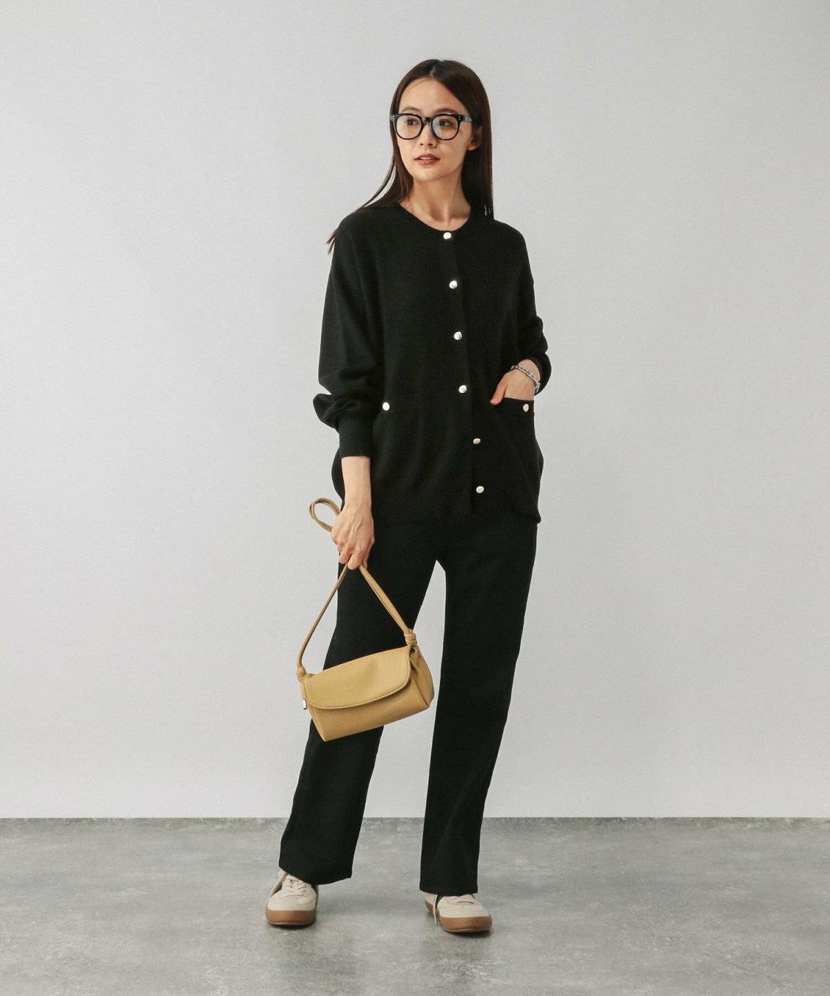 黒カーディガンに黒パンツを合わせた女性