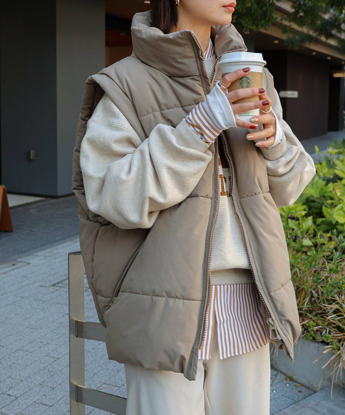 スウェットにダウンベストを重ねてパンツを合わせた女性