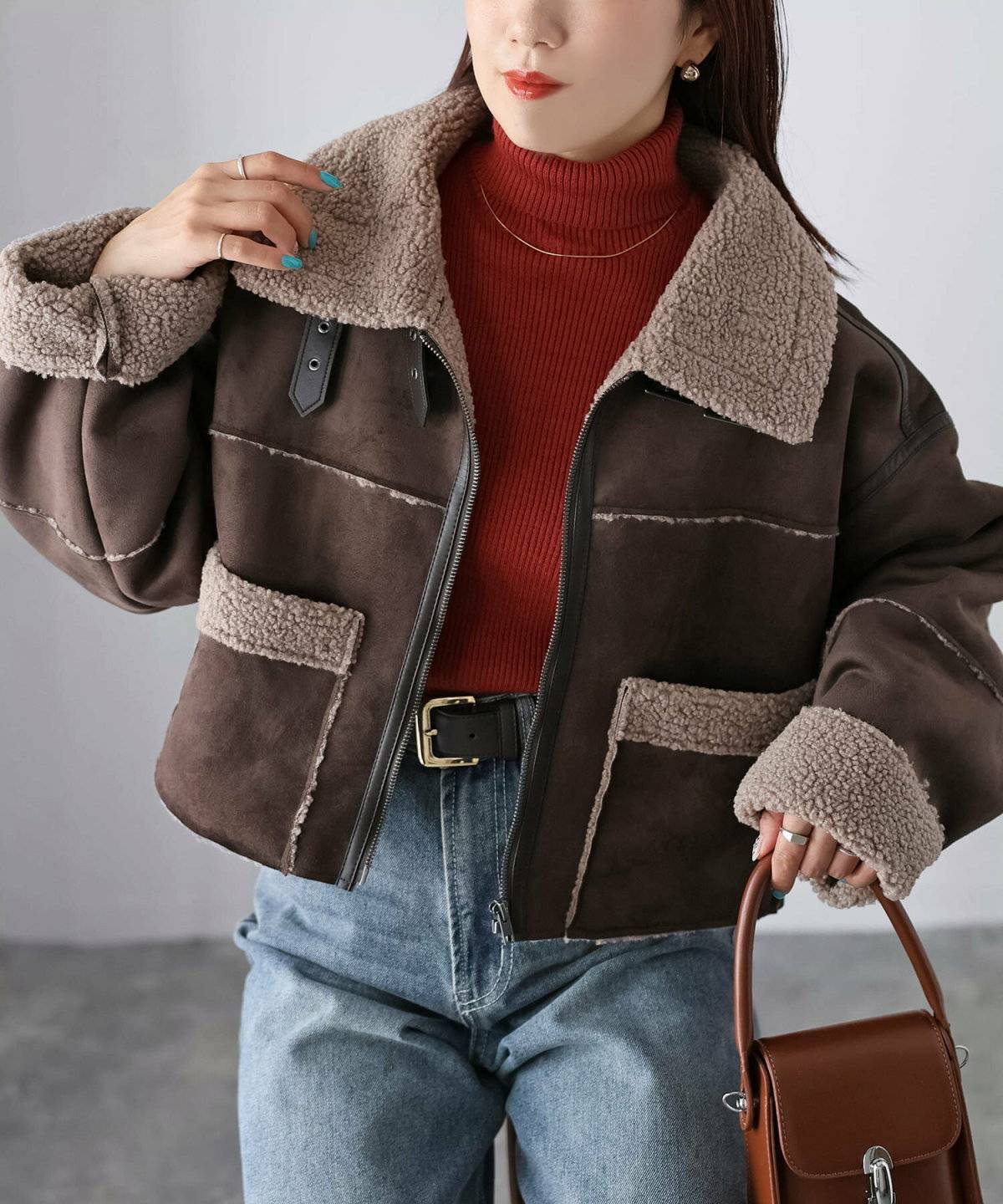 オレンジニットにボアアウターを羽織ってデニムを合わせた女性