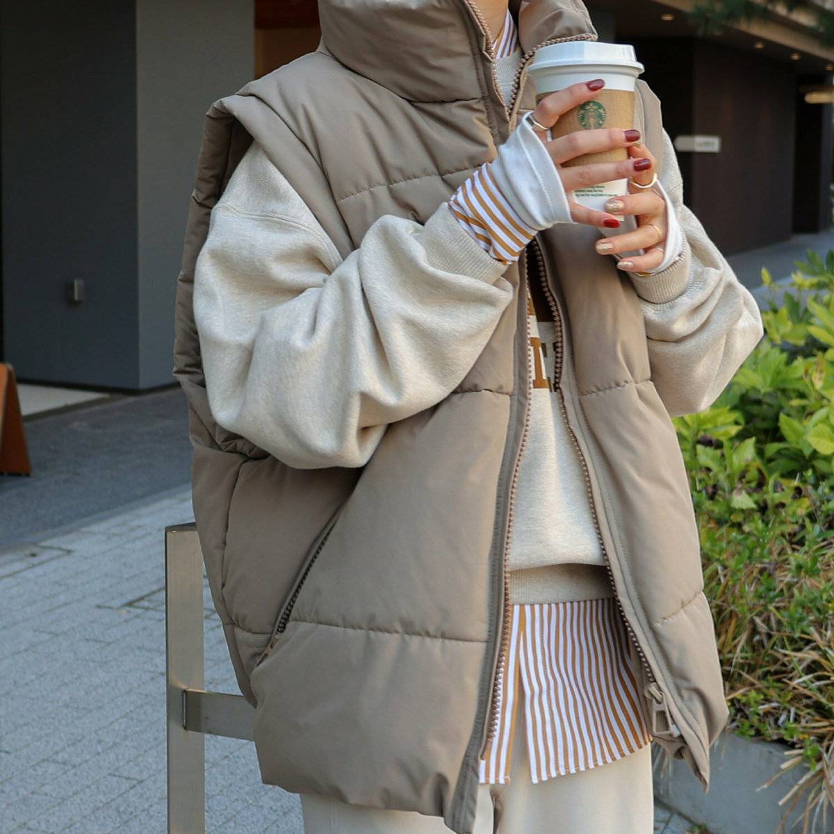 スウェットにダウンベストを重ねてパンツを合わせた女性