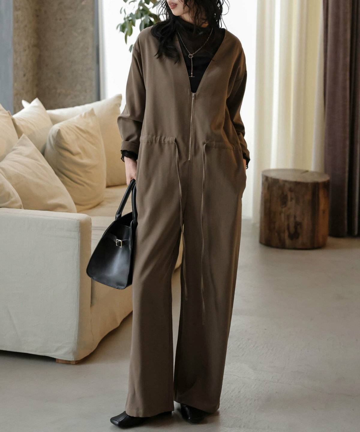 長袖オールインワンの下に長袖トップスを合わせた女性