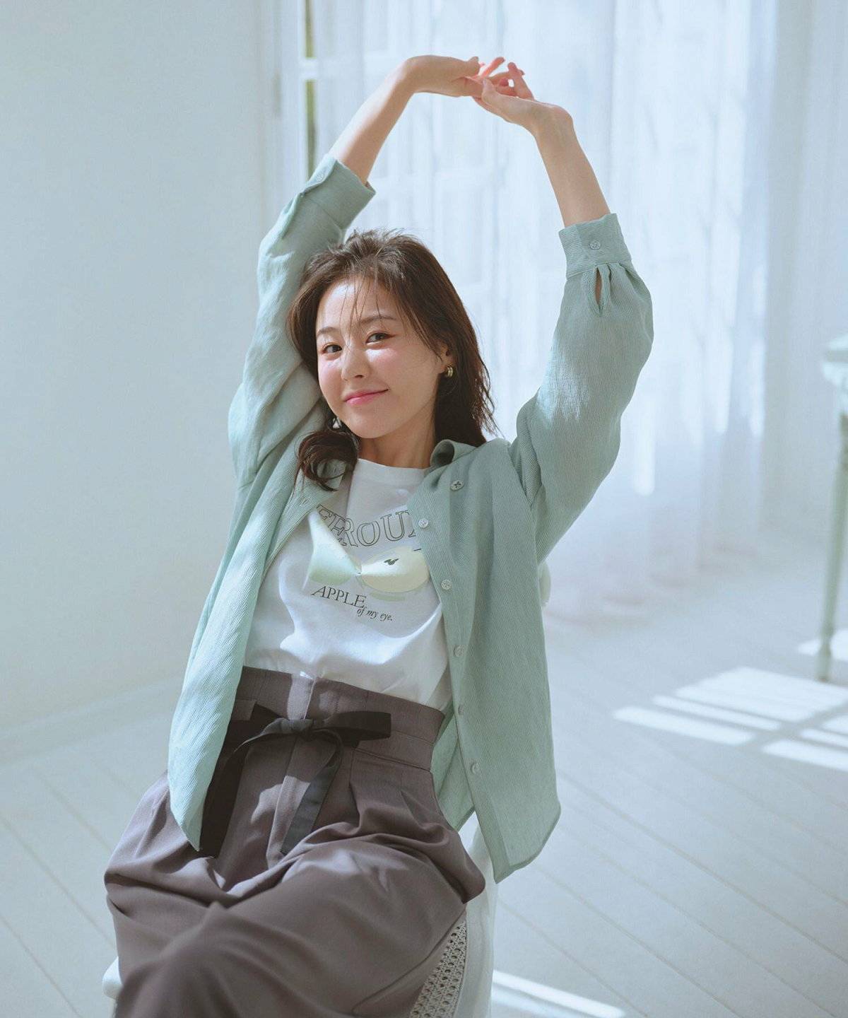 グリーンのシャツにグレーのパンツを合わせた女性