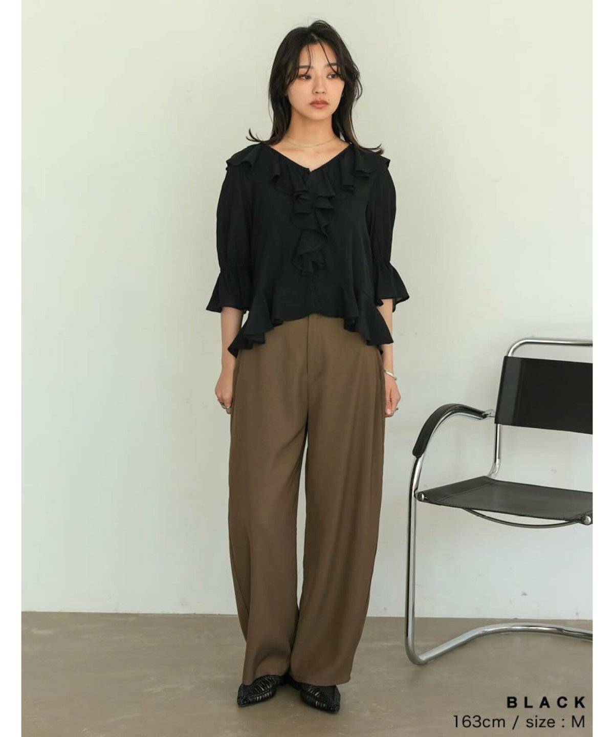 黒ブラウスにパンツを合わせた女性