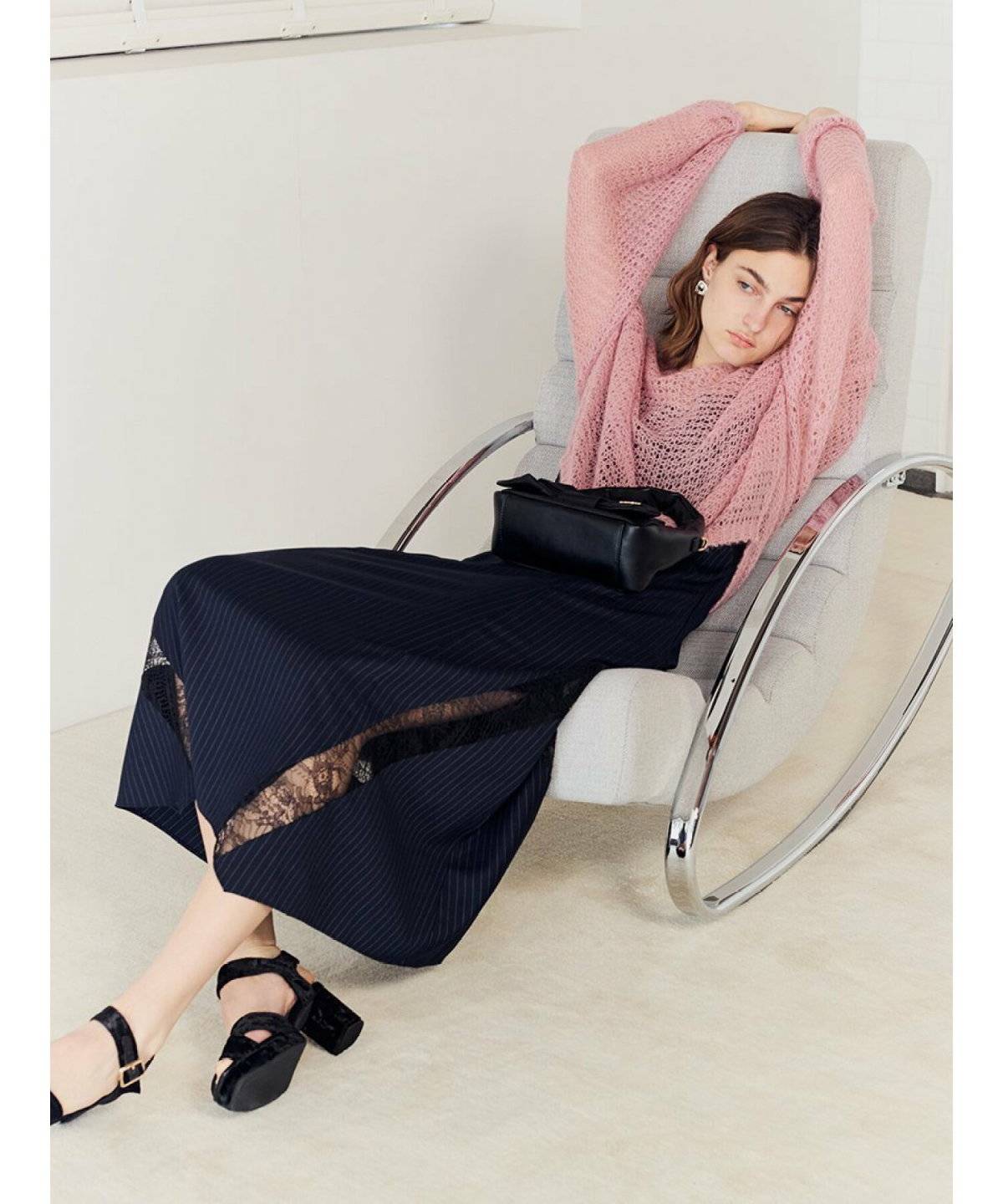 ピンクニットに黒スカートを合わせた女性