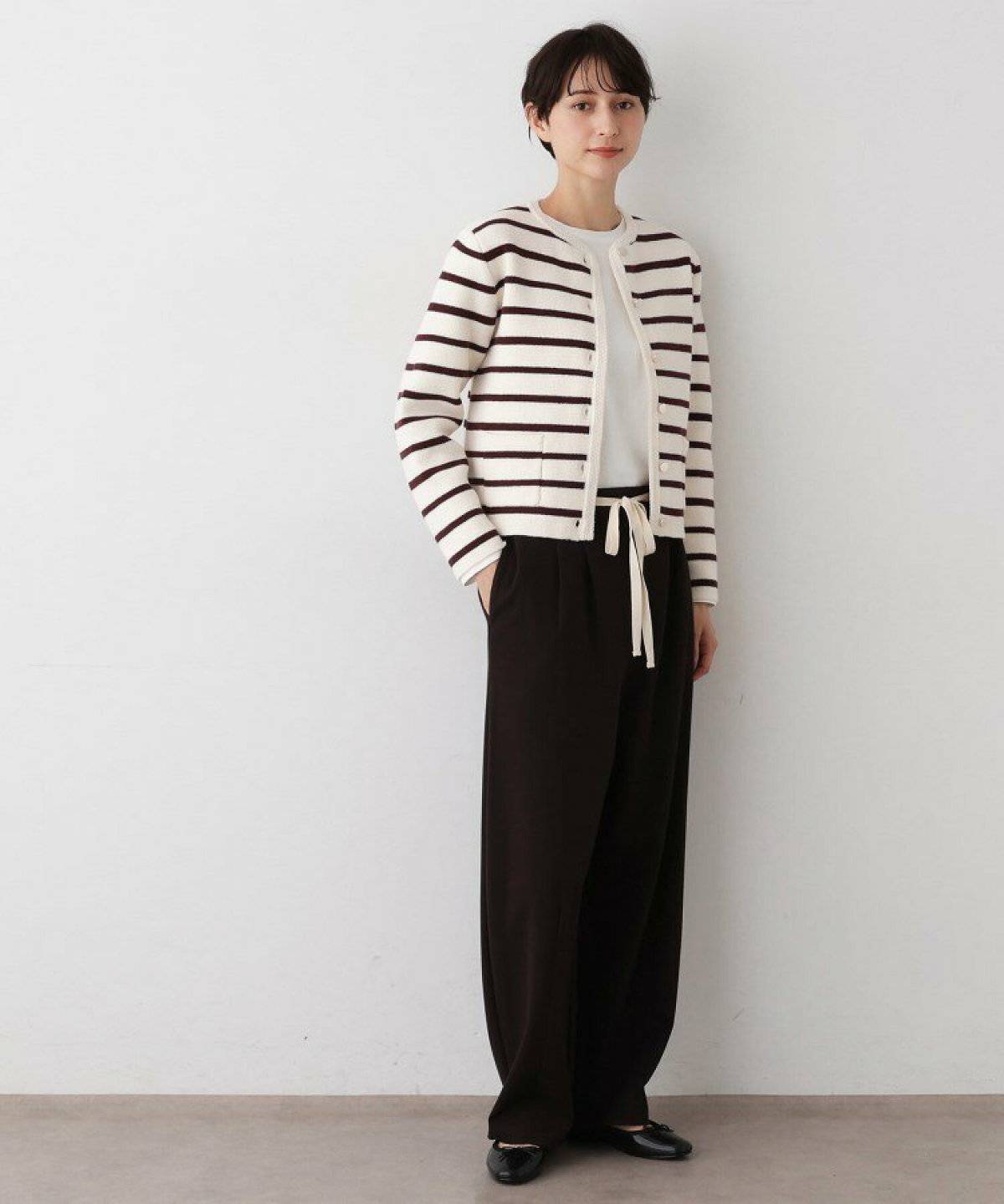 ボーダー柄カーディガンにブラウンのパンツを合わせた女性