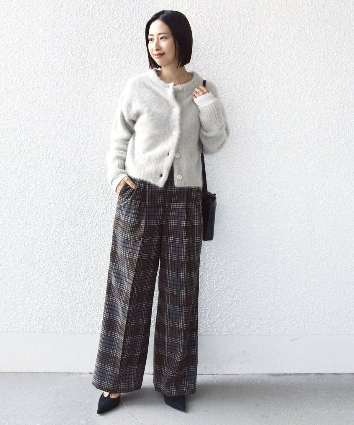 カーディガンにチェック柄パンツを合わせた女性