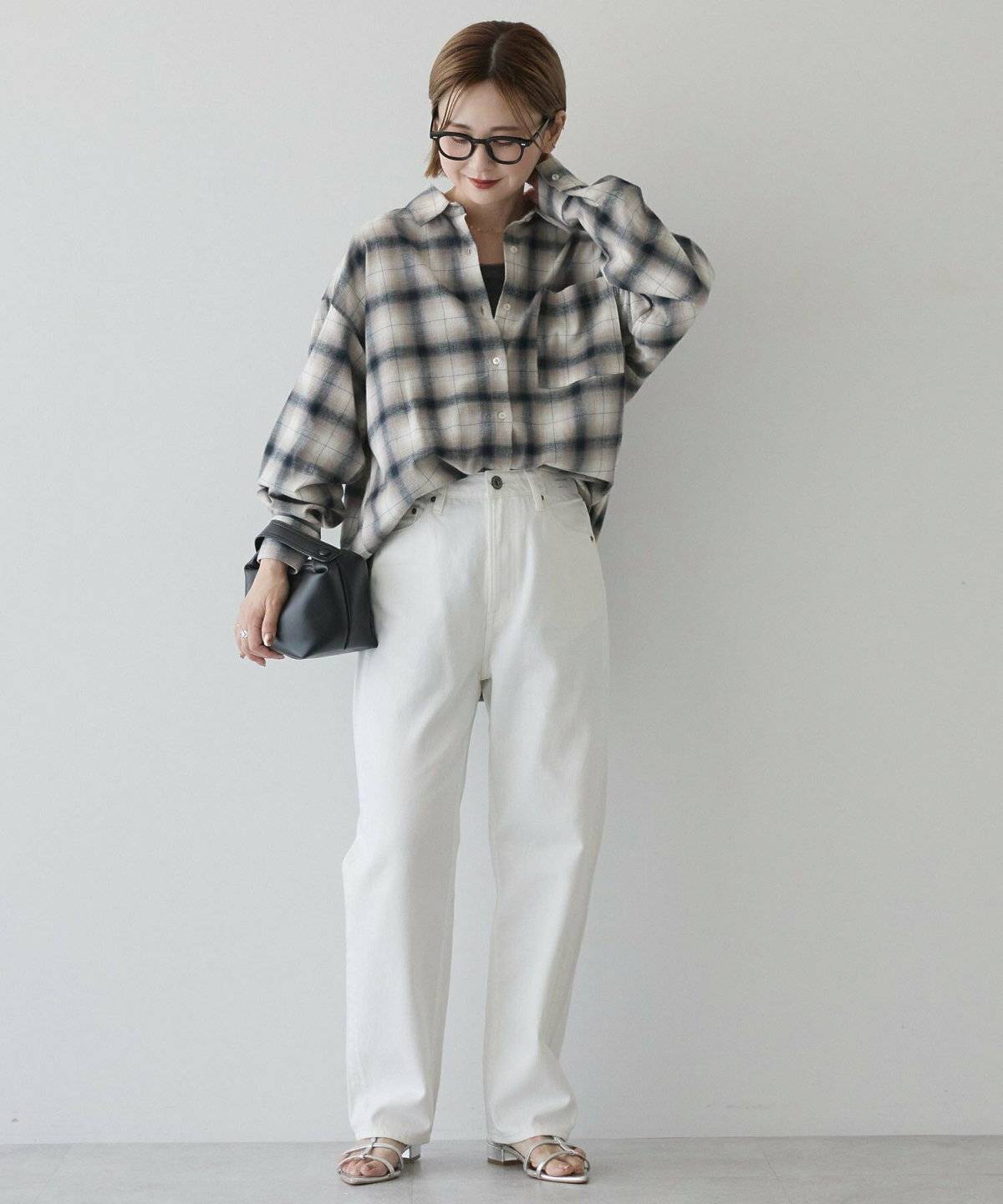 チェック柄シャツに白パンツを合わせた女性