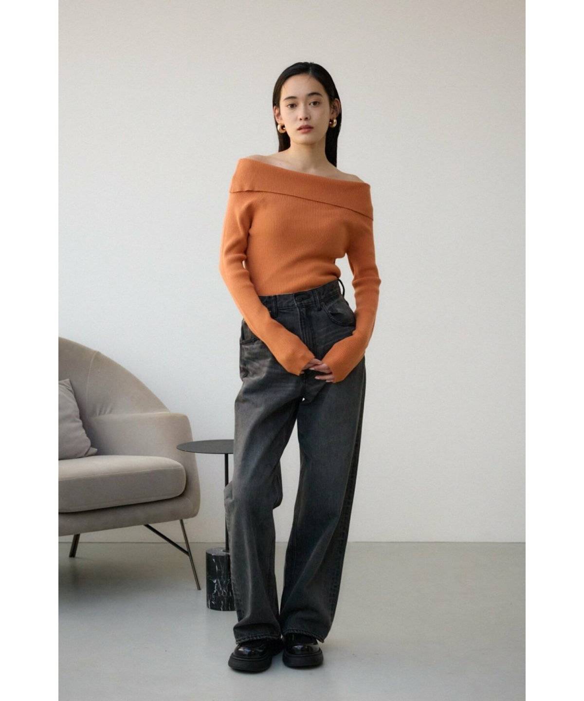 オレンジニットにデニムを合わせた女性