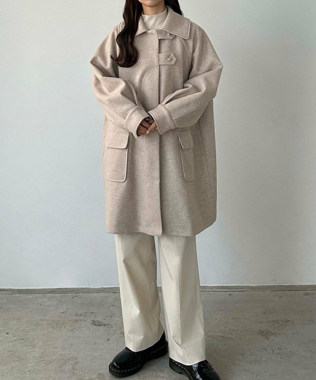白ニットにベージュパンツを合わせてベージュコートを羽織った女性