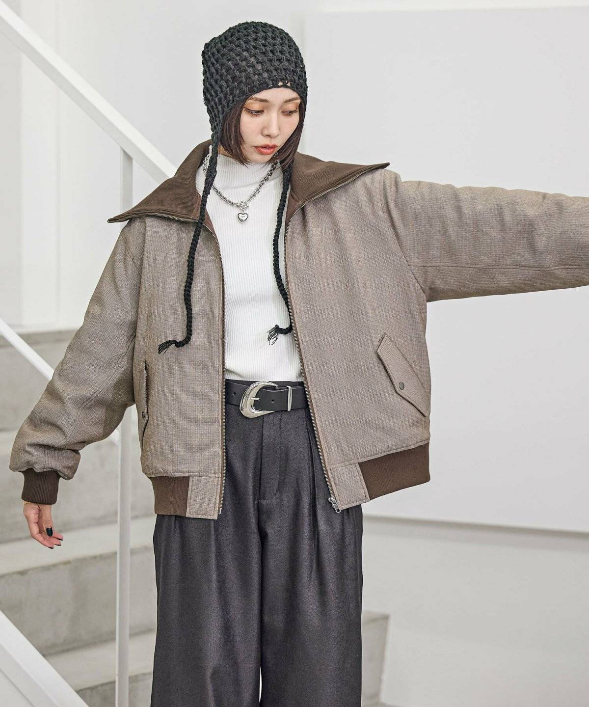 ブラウンのブルゾンにグレーのパンツを合わせた女性