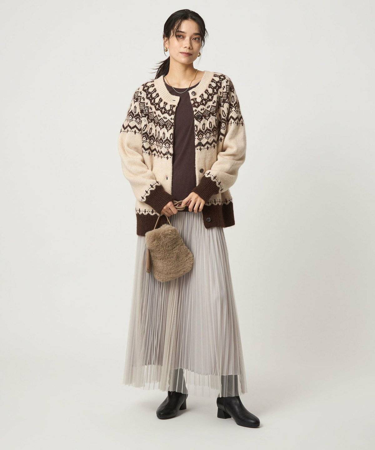 ニットにスカートを合わせて柄カーディガンを羽織った女性