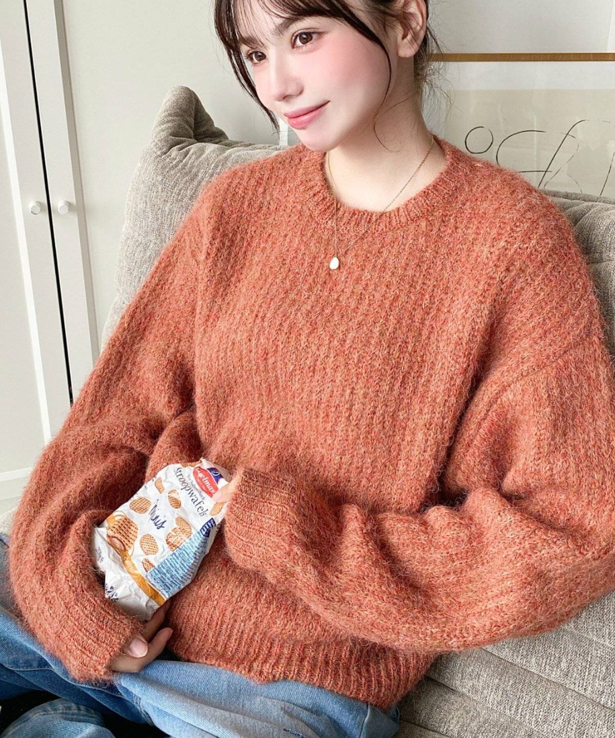 オレンジのニットにデニムを合わせた女性