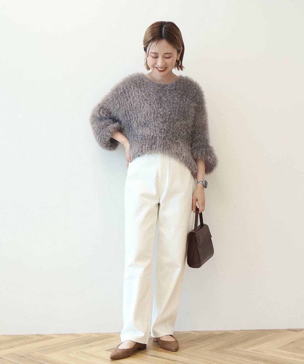 グレーニットに白パンツを合わせた女性