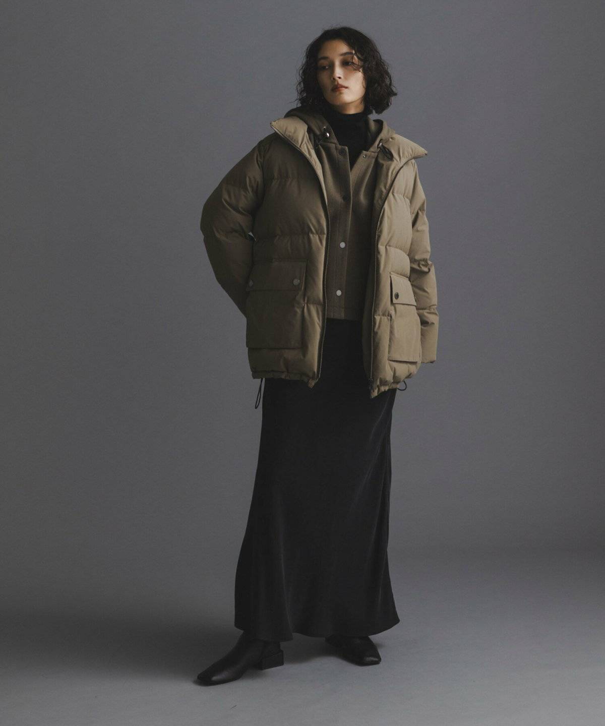 グリーンのダウンに黒スカートを合わせた女性