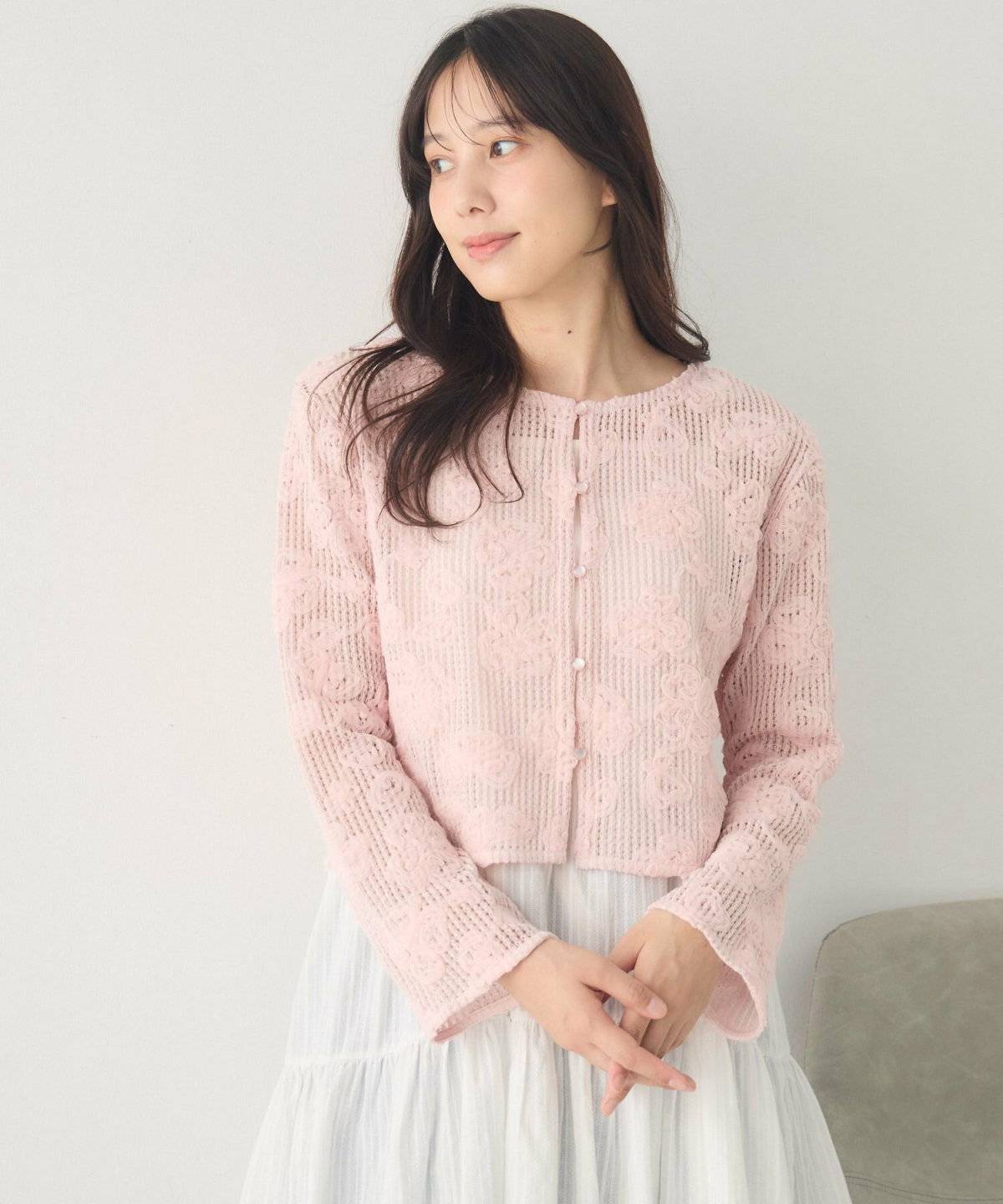 カーディガンにホワイトのスカートを合わせた女性