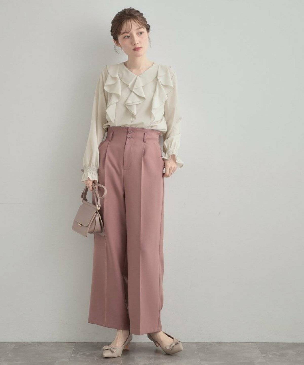 フリルブラウスにピンクパンツを合わせた女性