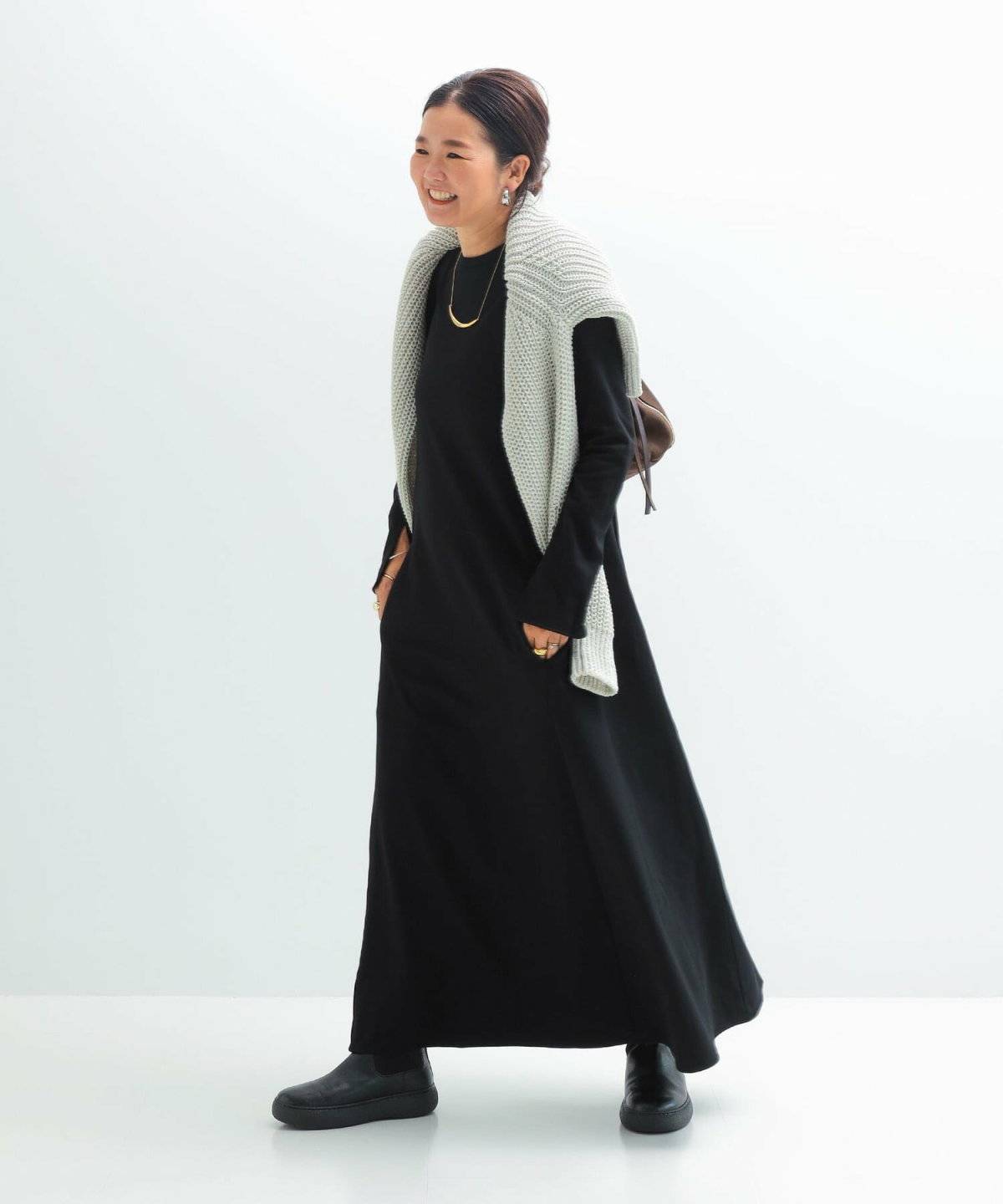 黒ワンピースにグリーンのカーディガンを羽織った女性