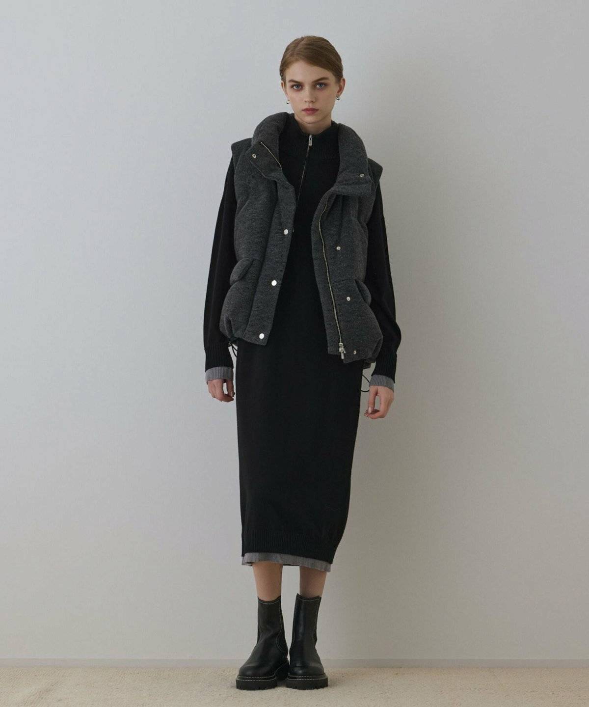 ニットワンピースにダウンベストを重ねた女性