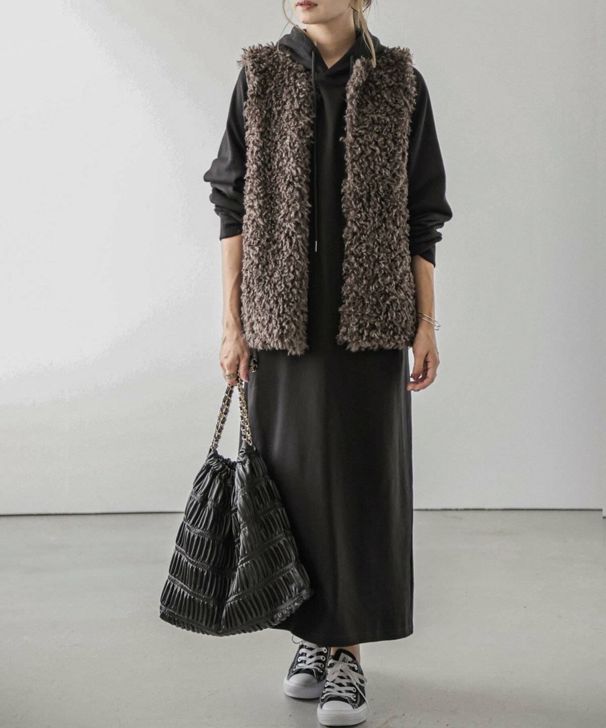 パーカーワンピースにベストを重ねた女性