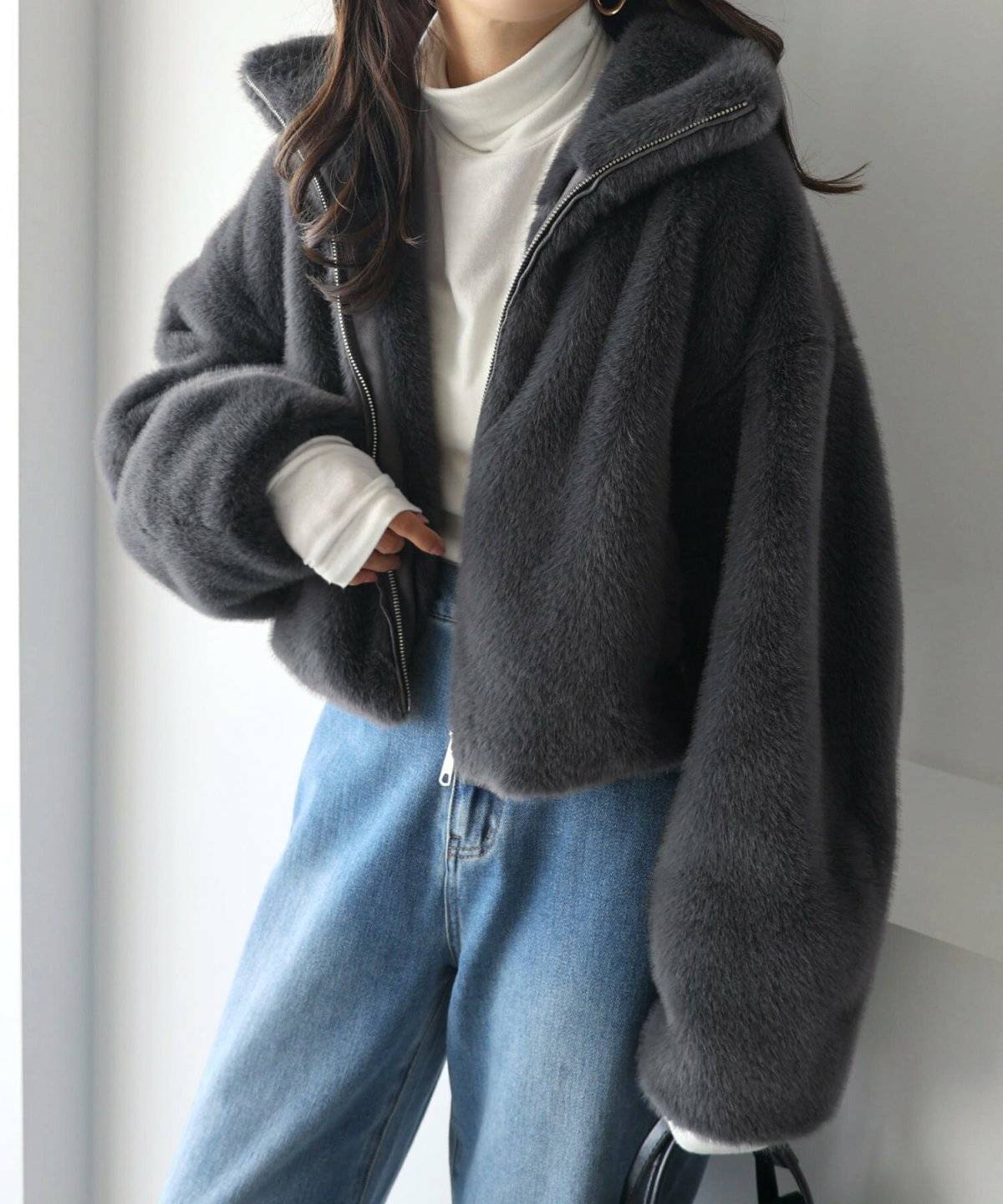 グレーのアウターにデニムを合わせた女性