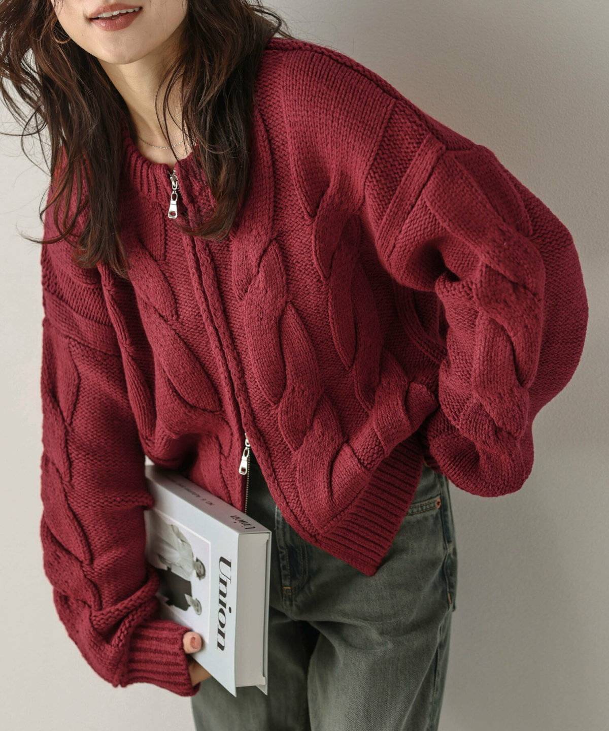 赤いカーディガンにデニムパンツを合わせた女性