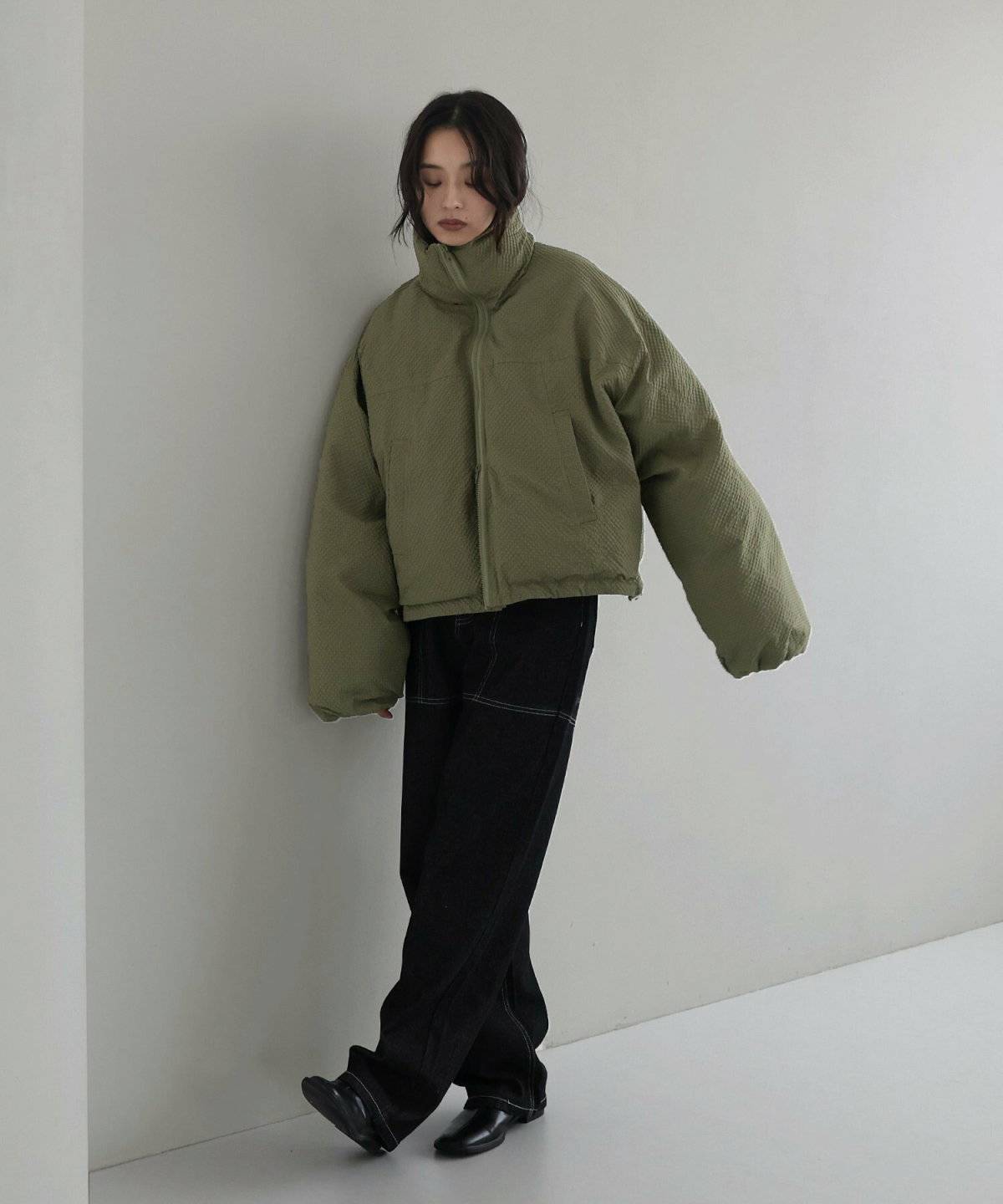 カーキのダウンジャケットに黒パンツを合わせた女性