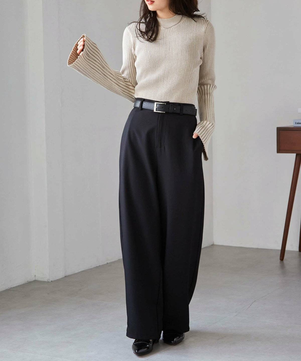 ベージュのニットに黒パンツを合わせた女性