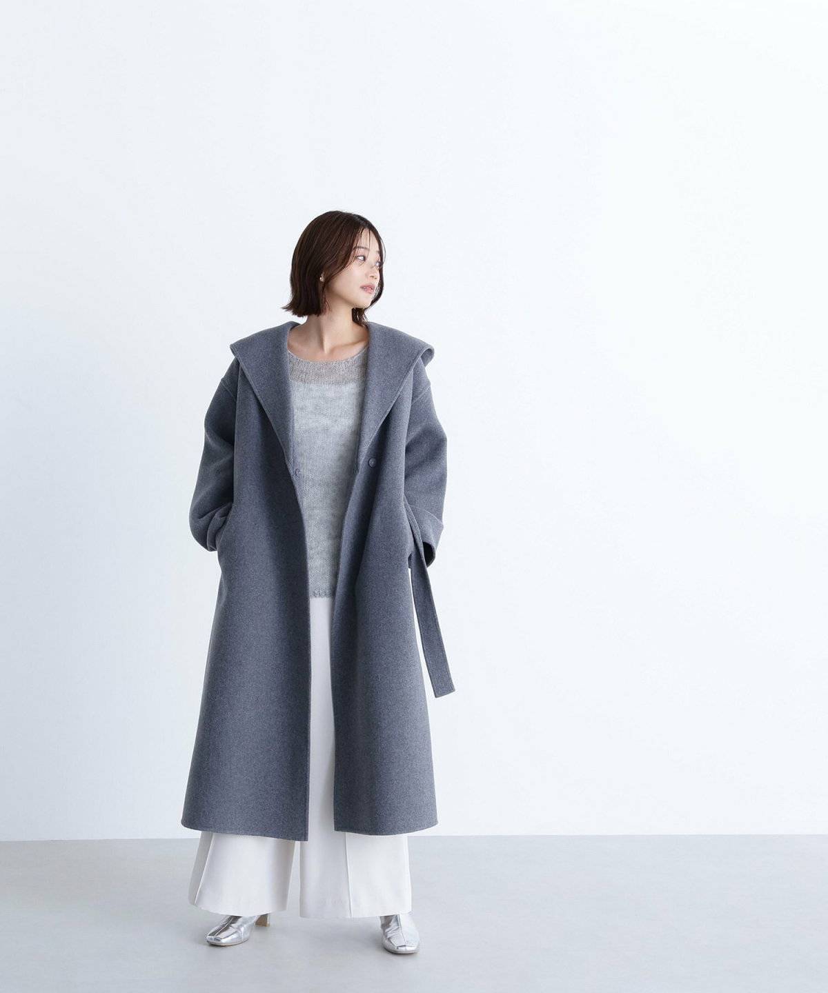 グレーのコートに白パンツを合わせた女性