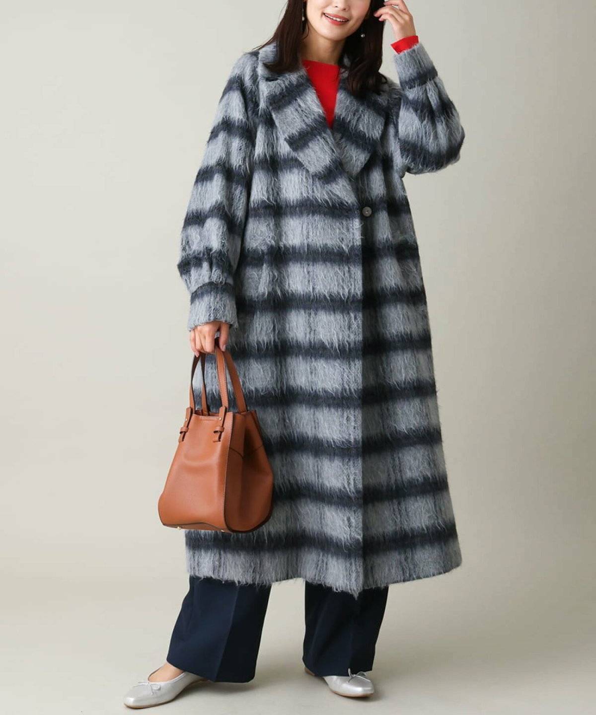 赤ニットにチェック柄コートを羽織った女性