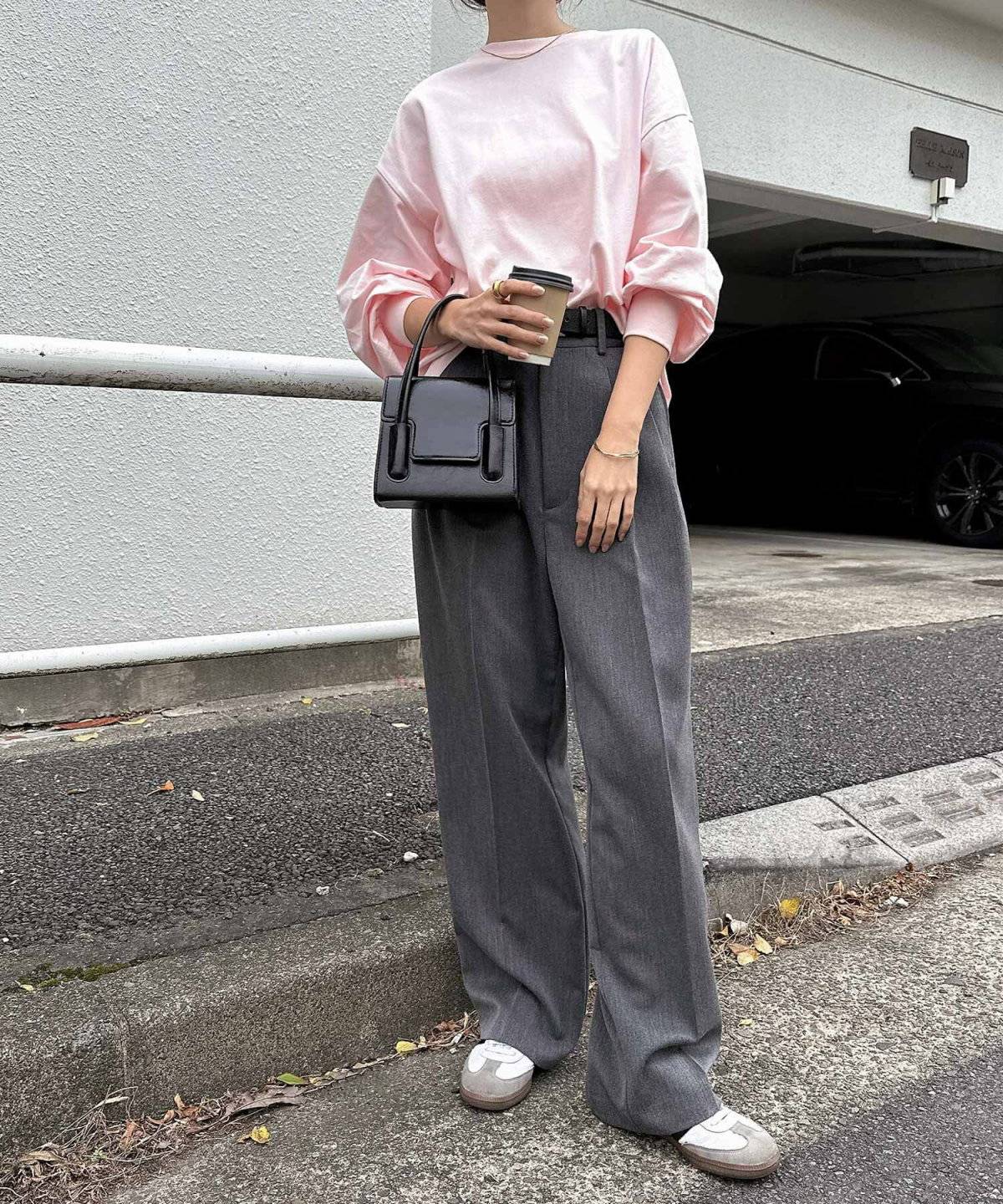 ピンクのトップスにグレーのパンツを合わせた女性