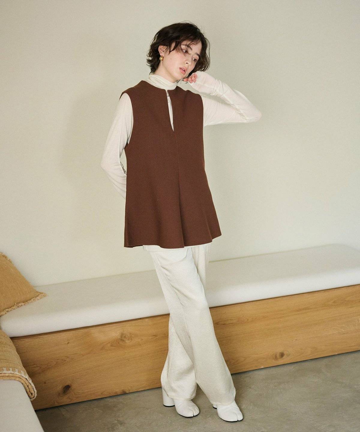 ホワイトコーデにブラウンのベストを重ねた女性