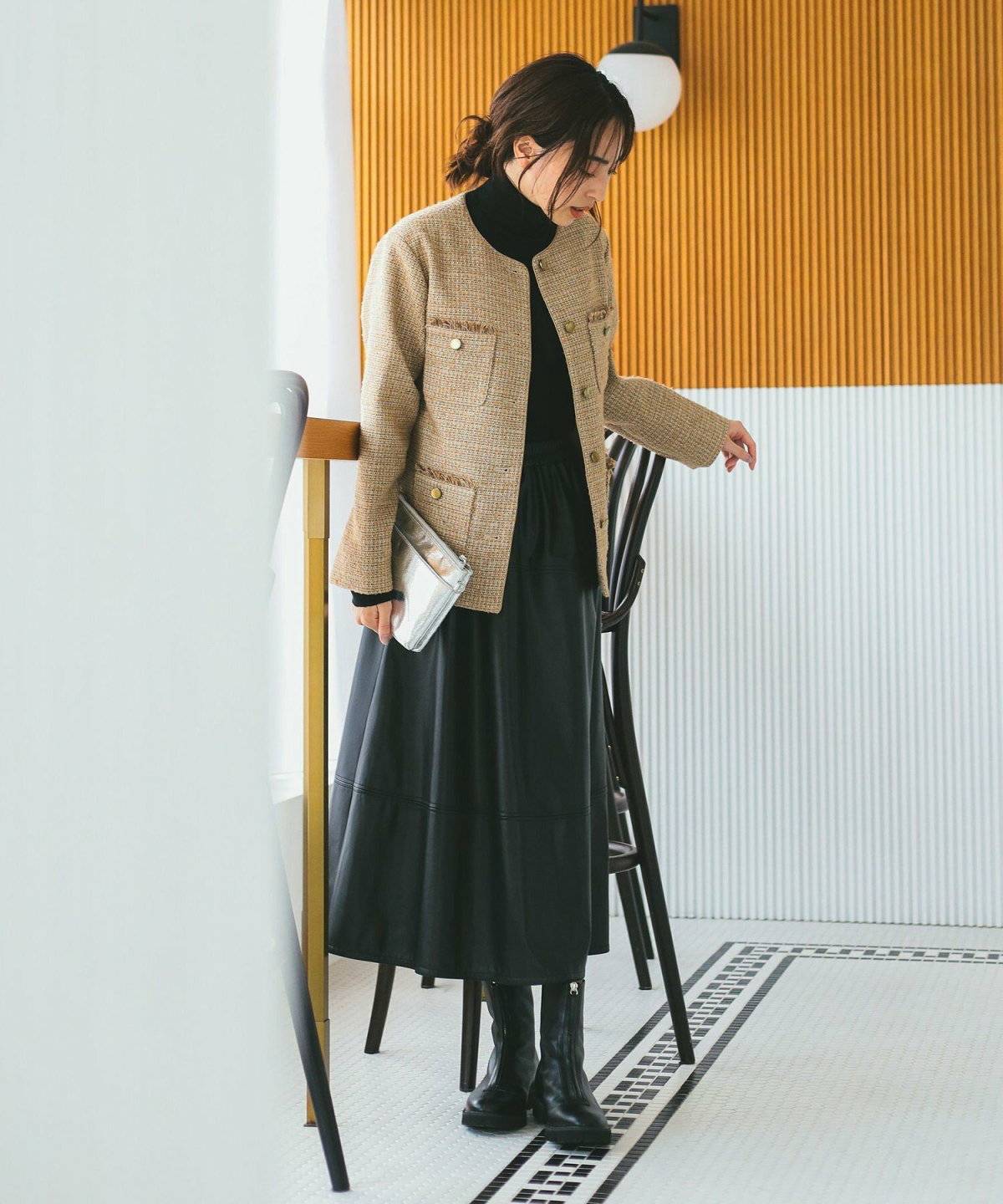 ブラックコーデにベージュのカーディガンを羽織った女性