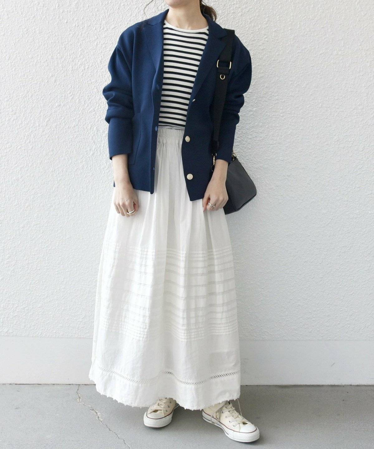 ホワイトコーデにネイビーのブレザーを羽織った女性