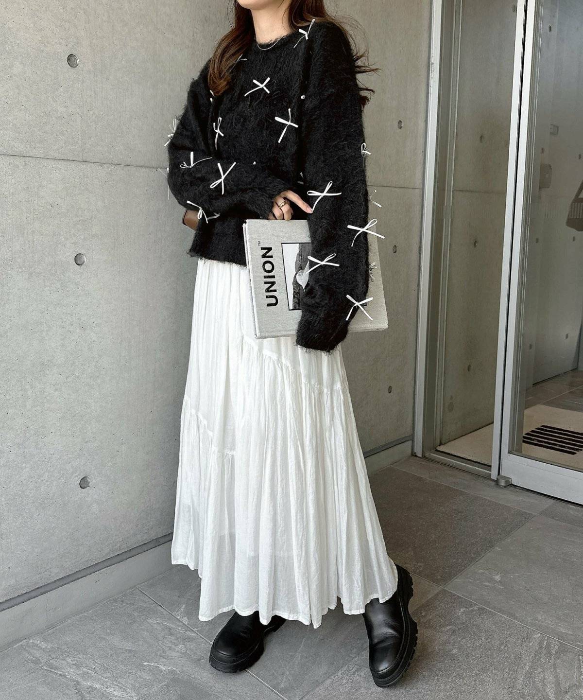 柄ニットに白スカートを合わせた女性