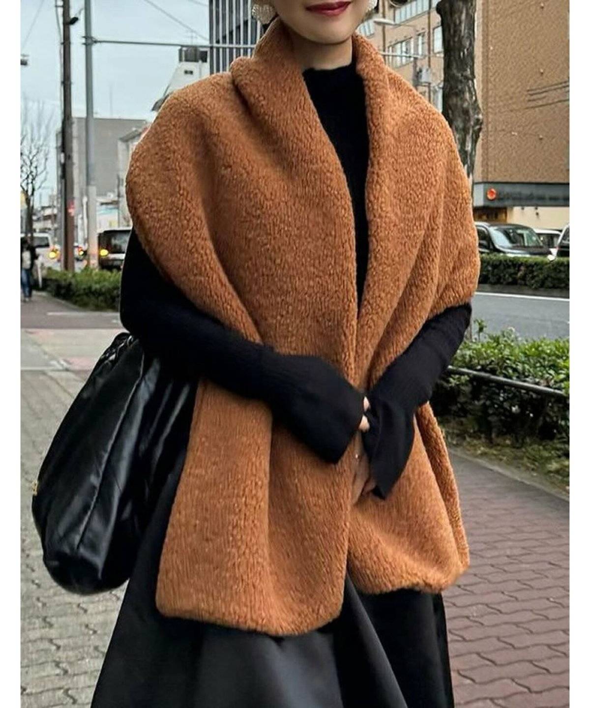 ブラックコーデにブラウンのマフラーを合わせた女性