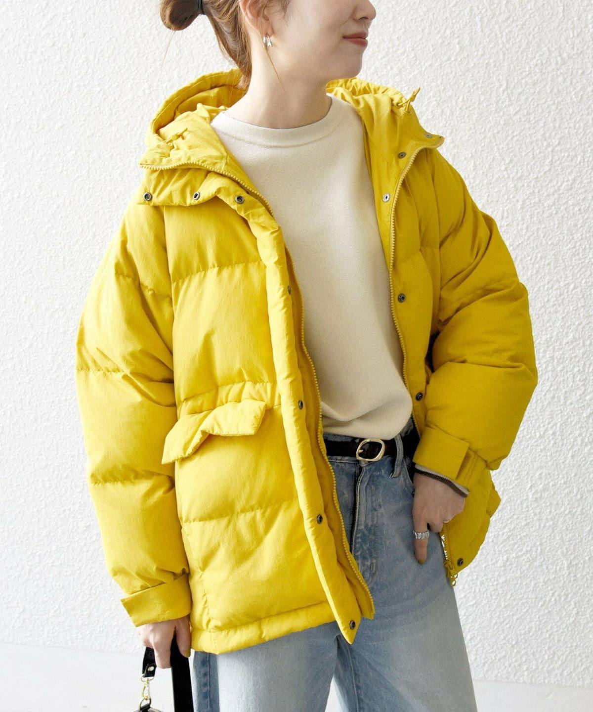 イエローのダウンにデニムを合わせた女性