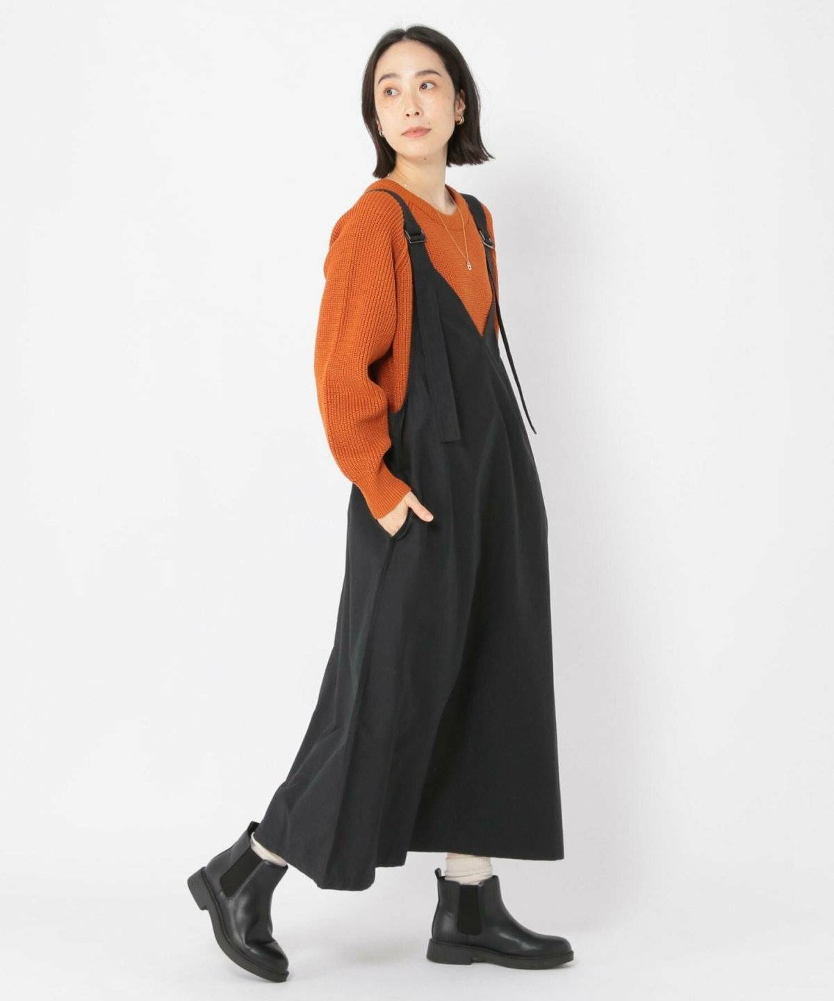 ニットに黒のジャンパースカートを合わせた女性