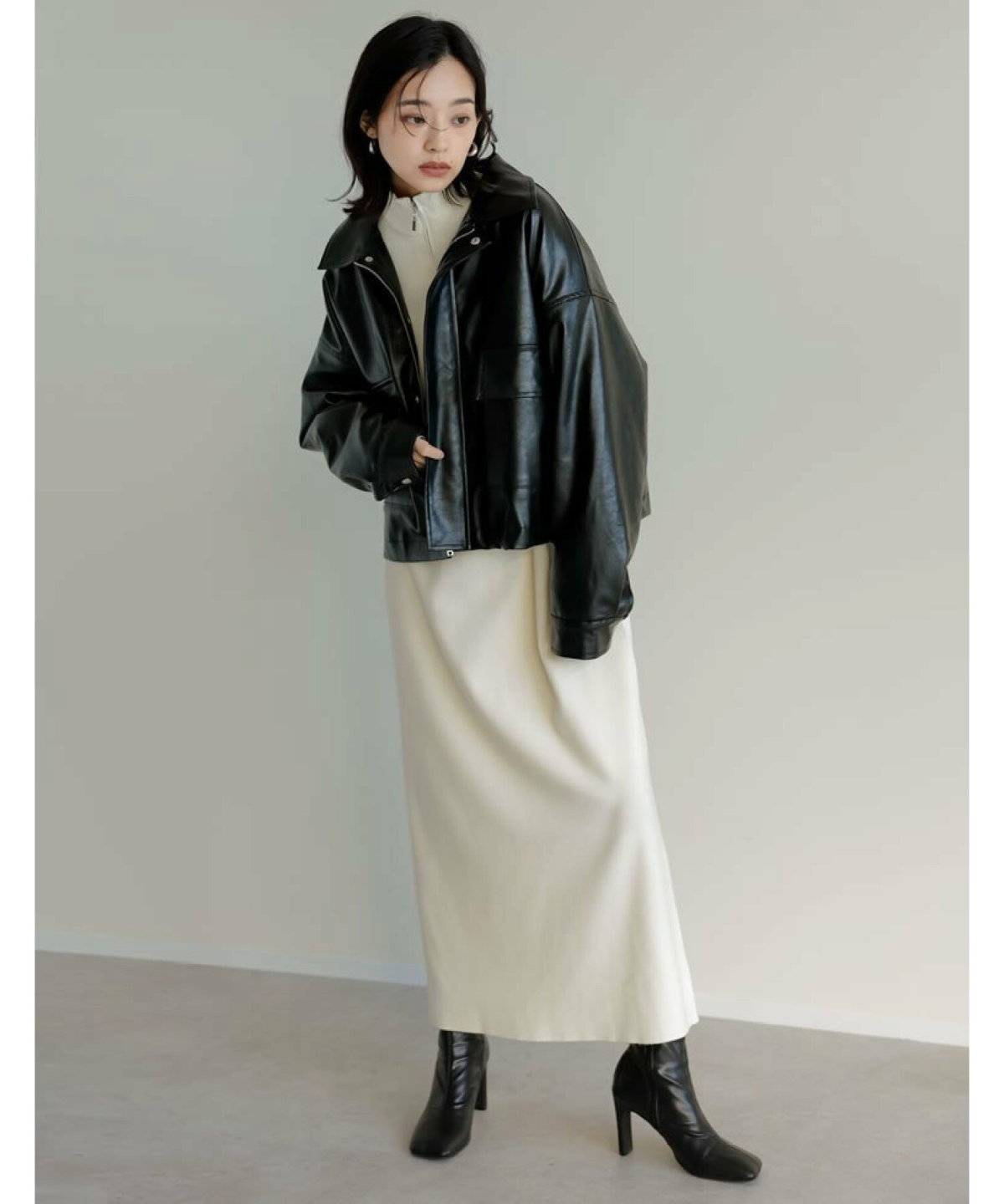 ニットワンピースに黒のジャケットを羽織った女性