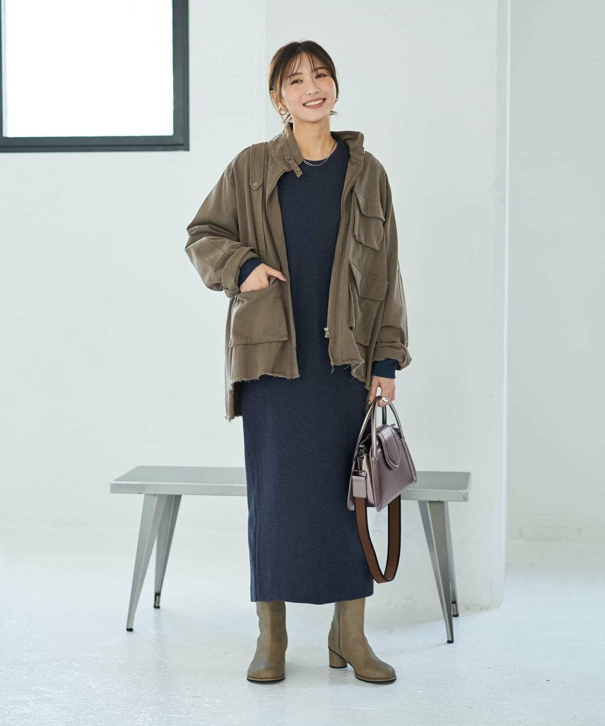 ニットワンピースにカーキのアウターを重ねた女性