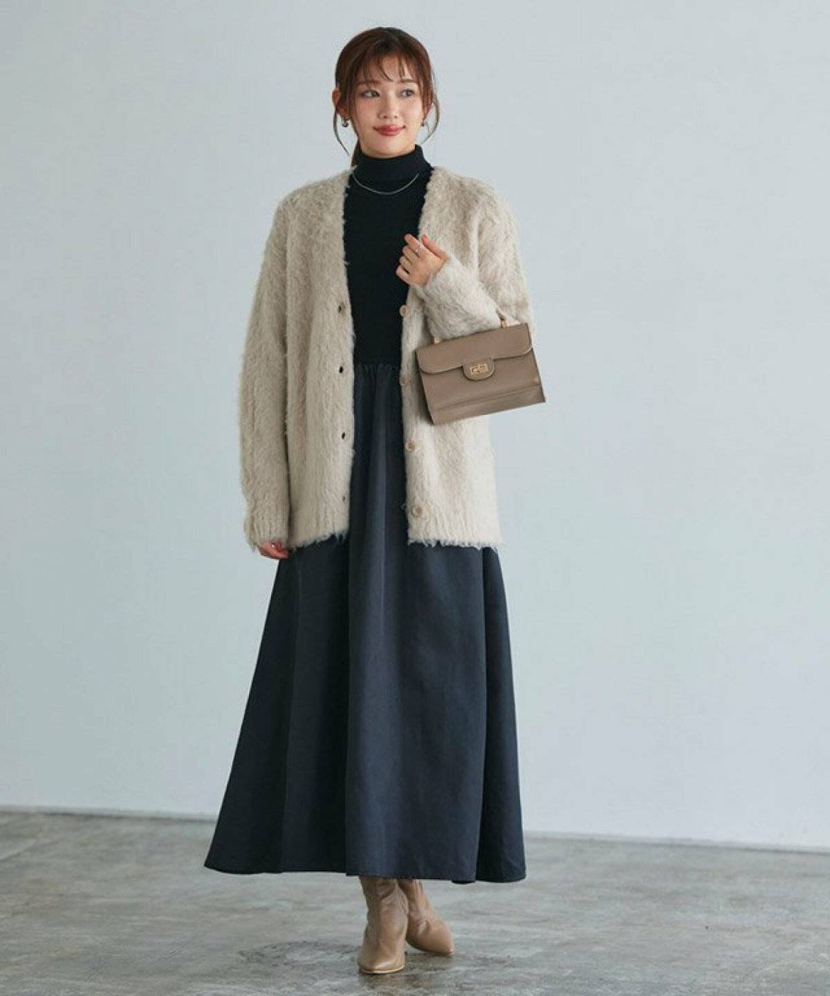 白アウターに黒のドッキングワンピースを合わせた女性