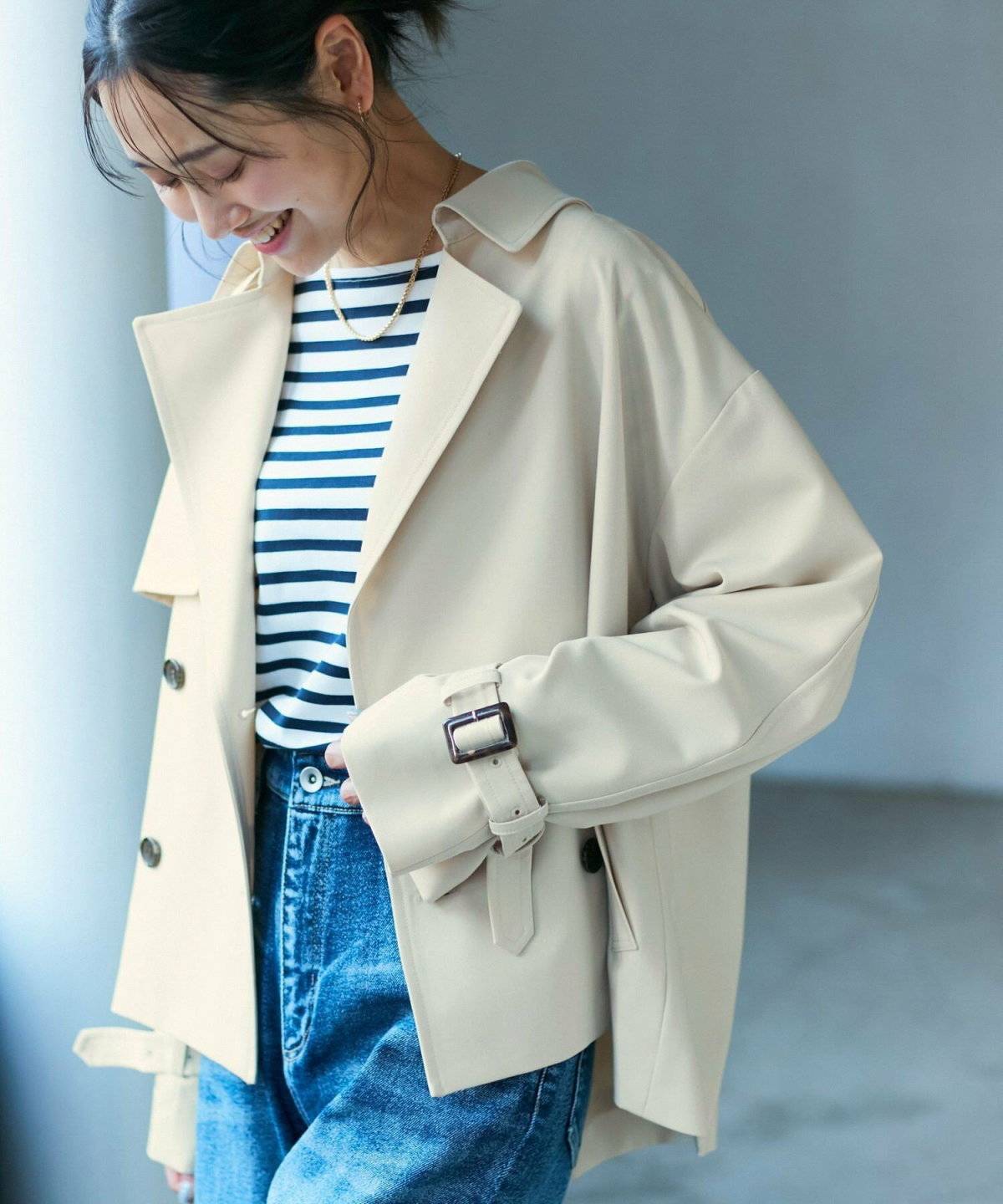 ボーダー柄トップスにデニムを合わせてトレンチコートを羽織った女性